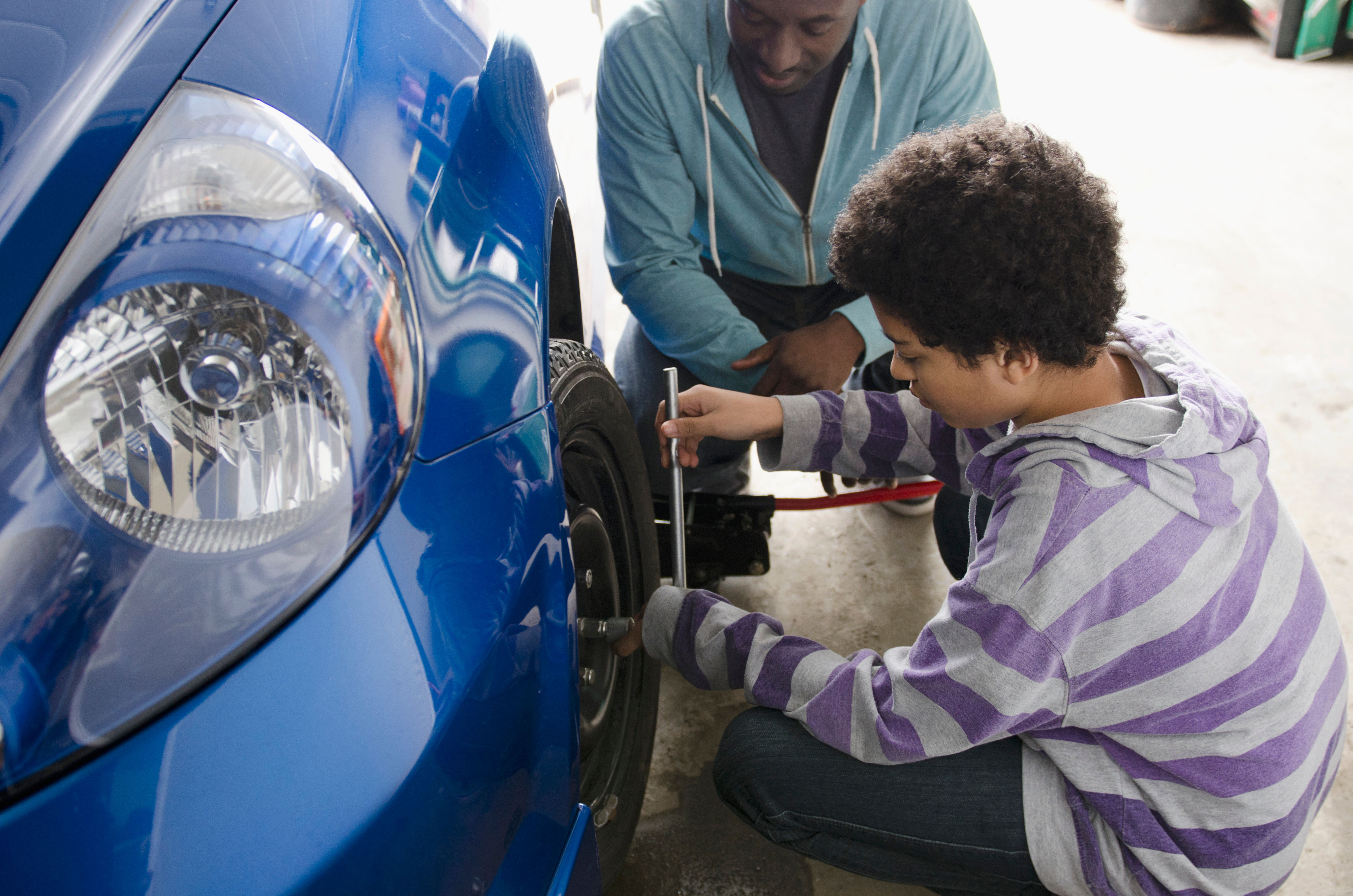 Teen learning life skills with car maintenance